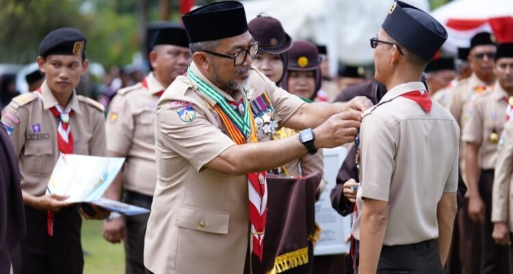 Sekda Provinsi Jambi Sudirman selaku Ka Kwarda menyematkan tanda peserta Apel Besar Hari Pramuka ke-64, di Tanjung Jabung Timur